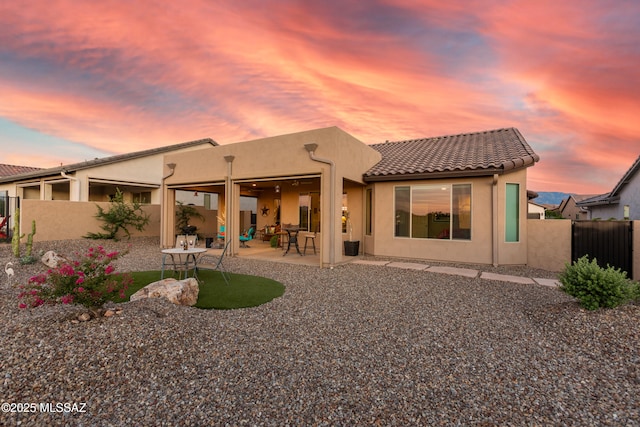 back house at dusk featuring a patio area