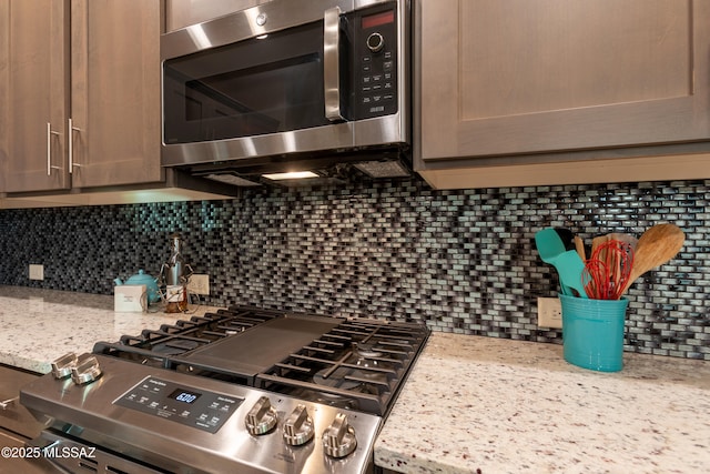 kitchen with decorative backsplash, light stone countertops, and appliances with stainless steel finishes