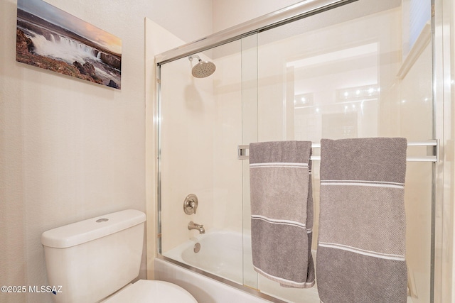 bathroom featuring toilet and bath / shower combo with glass door