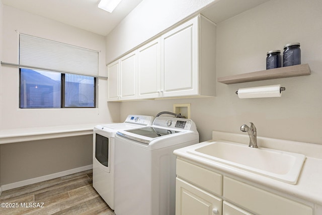 clothes washing area with cabinets, light hardwood / wood-style floors, sink, and washer and dryer