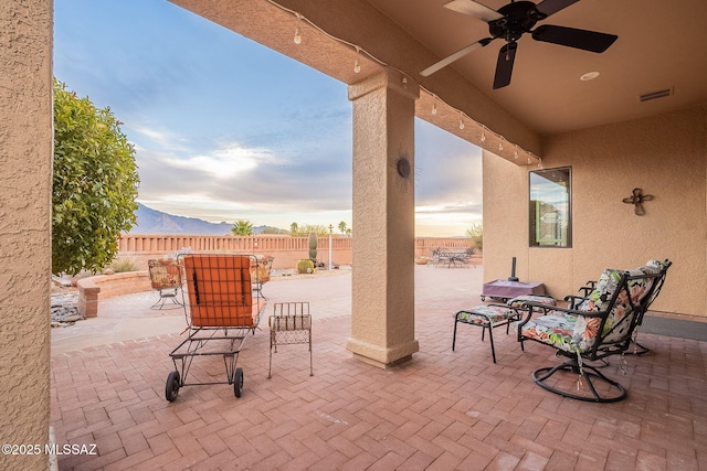 patio terrace at dusk featuring a mountain view and ceiling fan