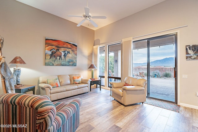 living room with a mountain view, light hardwood / wood-style floors, and ceiling fan