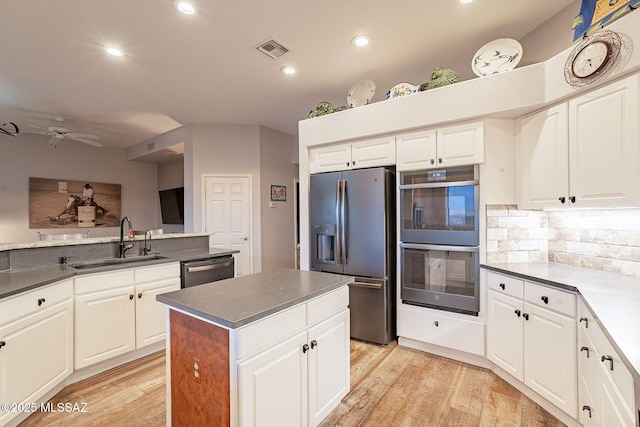 kitchen with sink, white cabinetry, tasteful backsplash, light wood-type flooring, and appliances with stainless steel finishes