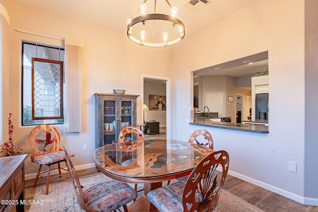 dining space featuring sink, hardwood / wood-style floors, and a notable chandelier