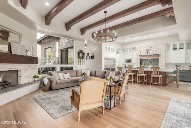 living room with an inviting chandelier, light wood-type flooring, beam ceiling, and a fireplace