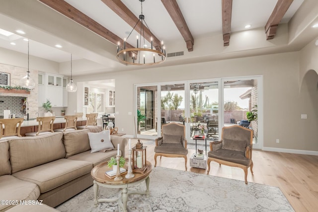 living room with light wood-type flooring, beam ceiling, and an inviting chandelier