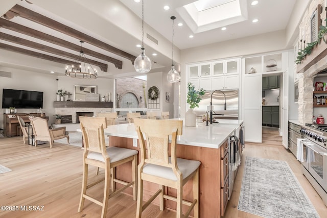 kitchen with high end appliances, white cabinetry, a large island, beam ceiling, and pendant lighting