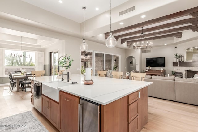 kitchen featuring sink, hanging light fixtures, a kitchen island with sink, and an inviting chandelier