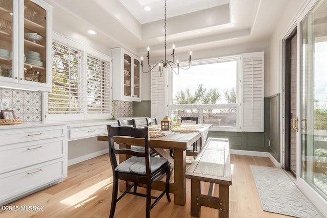 dining area featuring a chandelier, light hardwood / wood-style flooring, and a tray ceiling