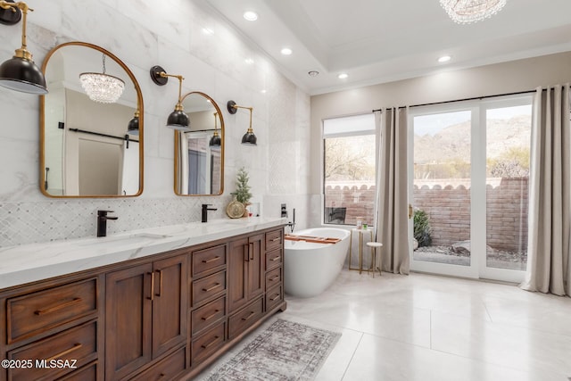 bathroom with tile walls, a bath, vanity, ornamental molding, and a chandelier