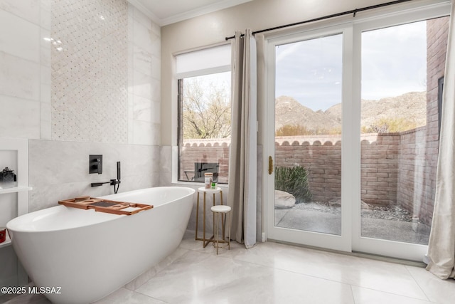 bathroom featuring a tub, plenty of natural light, tile walls, and a mountain view