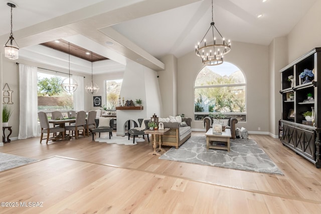 living room with a healthy amount of sunlight, a chandelier, light hardwood / wood-style flooring, and a raised ceiling