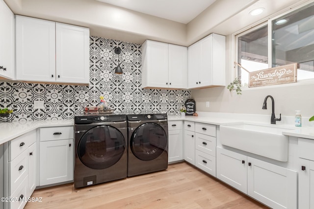 laundry room with cabinets, sink, light hardwood / wood-style flooring, and washing machine and dryer