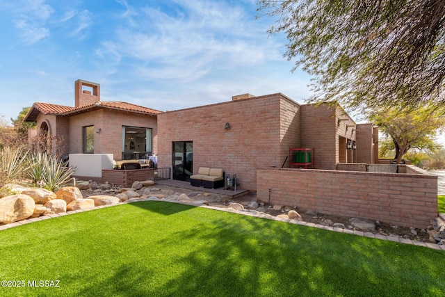 rear view of property with a lawn and outdoor lounge area