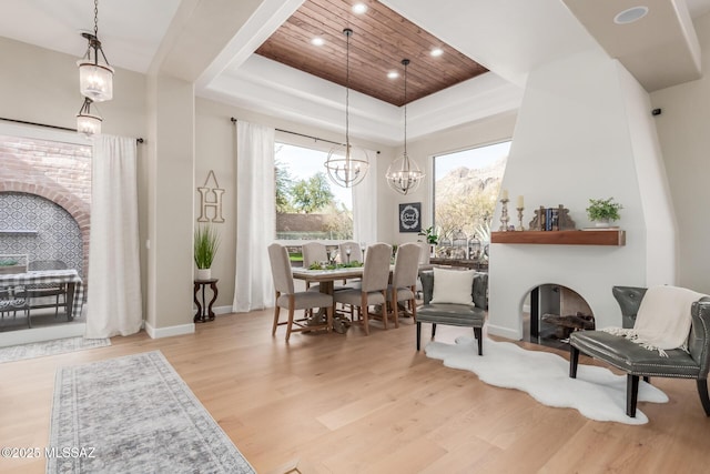 dining area featuring light hardwood / wood-style floors, wooden ceiling, a raised ceiling, and a chandelier