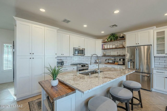 kitchen featuring tasteful backsplash, open shelves, a sink, high quality appliances, and visible vents