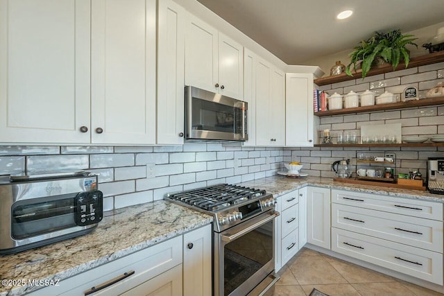 kitchen featuring backsplash, light tile patterned flooring, white cabinetry, and appliances with stainless steel finishes