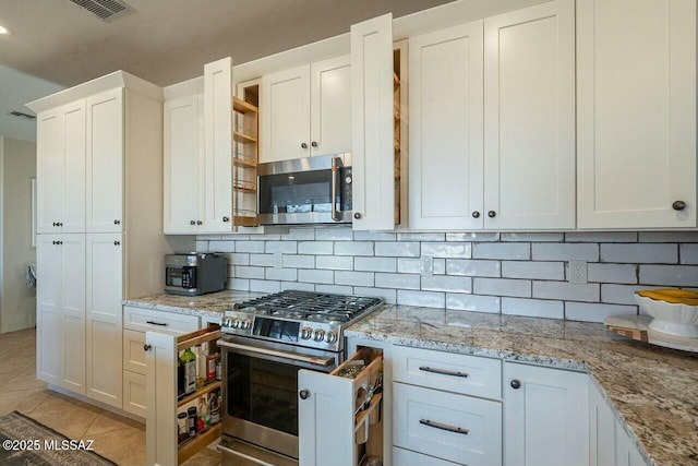 kitchen featuring white cabinets, visible vents, stainless steel appliances, backsplash, and light tile patterned floors