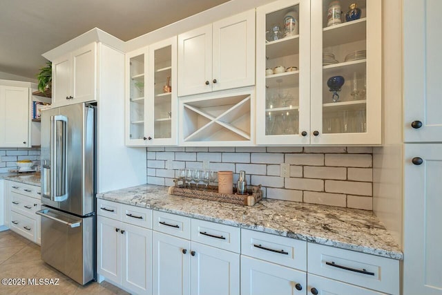 kitchen featuring high end fridge, light stone countertops, white cabinetry, and light tile patterned floors