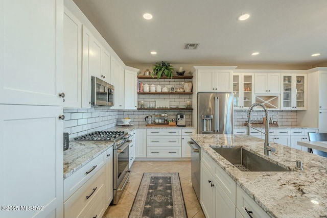 kitchen with white cabinetry, high quality appliances, a sink, and light tile patterned floors
