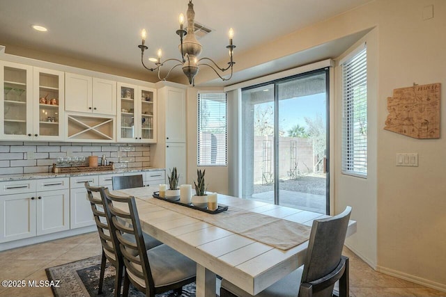 dining space featuring light tile patterned floors, baseboards, a chandelier, and visible vents