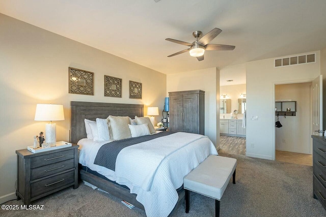 carpeted bedroom with baseboards, connected bathroom, visible vents, and ceiling fan