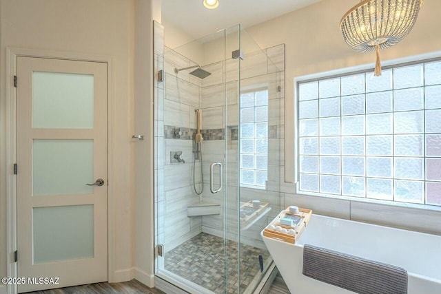 full bath with a soaking tub, a stall shower, and a chandelier