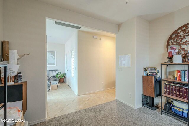 hallway featuring baseboards, carpet flooring, visible vents, and tile patterned flooring