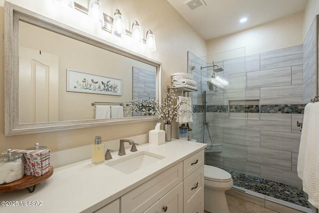bathroom featuring toilet, vanity, a shower stall, and visible vents