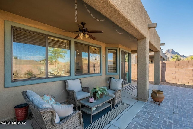 view of patio featuring an outdoor hangout area, fence, and ceiling fan
