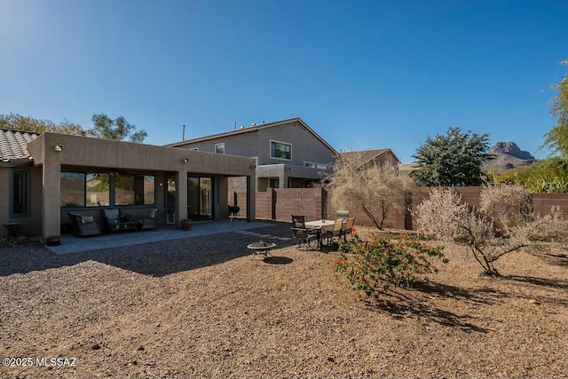 rear view of house featuring a fenced backyard, stucco siding, and a patio area
