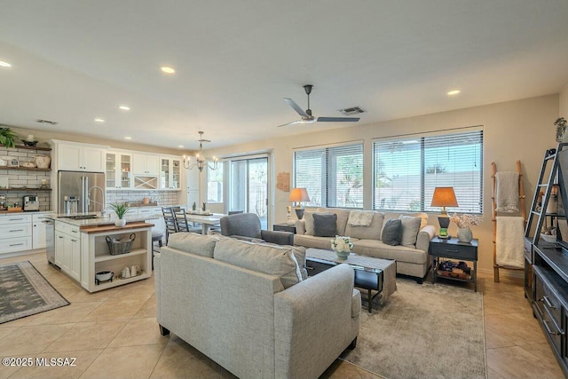 living area featuring light tile patterned flooring, ceiling fan with notable chandelier, visible vents, and recessed lighting