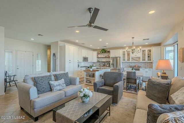 living room featuring light tile patterned floors, visible vents, recessed lighting, and ceiling fan with notable chandelier