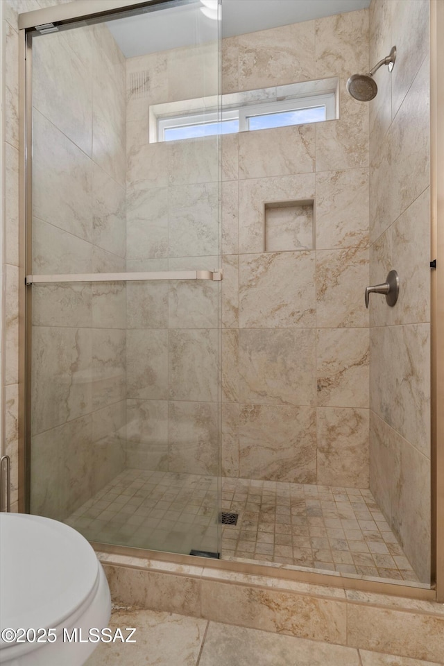 bathroom featuring toilet and a shower with door