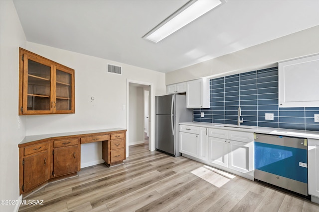 kitchen featuring white cabinets, appliances with stainless steel finishes, tasteful backsplash, sink, and light hardwood / wood-style flooring