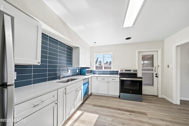 kitchen featuring sink, tasteful backsplash, white cabinetry, light hardwood / wood-style floors, and stainless steel appliances