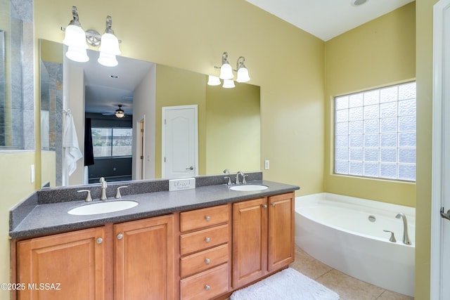 bathroom with tile patterned flooring, vanity, a healthy amount of sunlight, and a tub to relax in