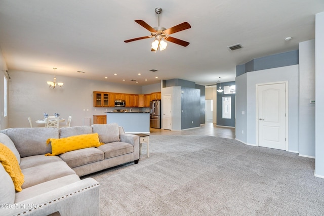 carpeted living room with ceiling fan with notable chandelier