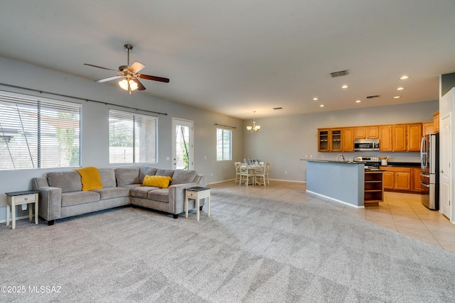 living room with sink, ceiling fan with notable chandelier, and light tile patterned floors