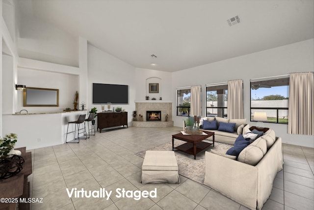 living room with light tile patterned flooring, a fireplace, and high vaulted ceiling