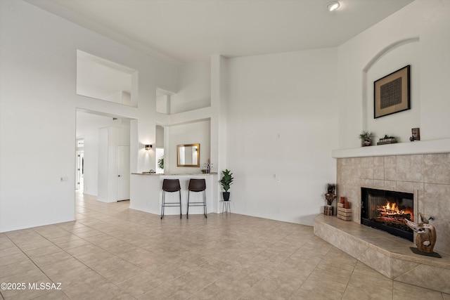 tiled living room featuring a tiled fireplace and a towering ceiling