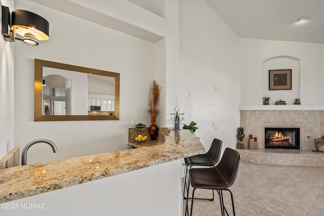 bar featuring light stone counters, a fireplace, and light tile patterned floors