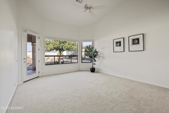 carpeted empty room featuring a high ceiling and ceiling fan