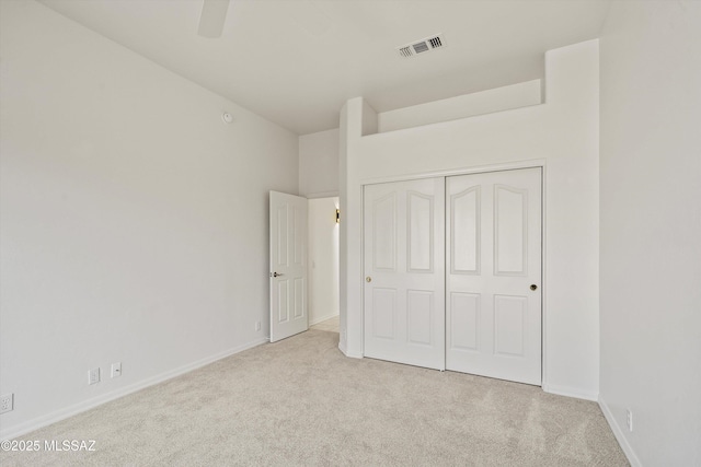 unfurnished bedroom with ceiling fan, a closet, and light carpet