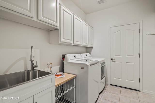 laundry area featuring cabinets, light tile patterned floors, sink, and washing machine and clothes dryer