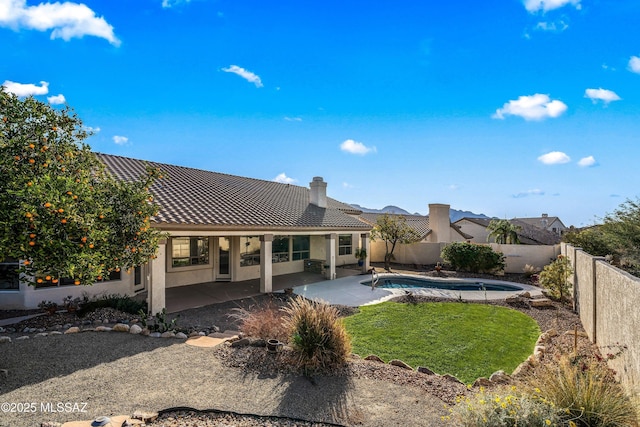 rear view of house featuring a fenced in pool and a patio area