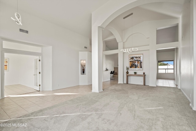 unfurnished living room featuring light carpet and high vaulted ceiling