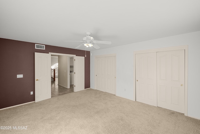 unfurnished bedroom with multiple closets, ceiling fan, and carpet