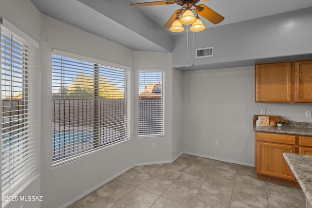 unfurnished dining area featuring light tile patterned floors and ceiling fan