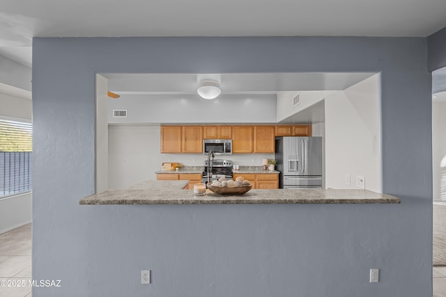 kitchen featuring light tile patterned floors, stainless steel appliances, and kitchen peninsula